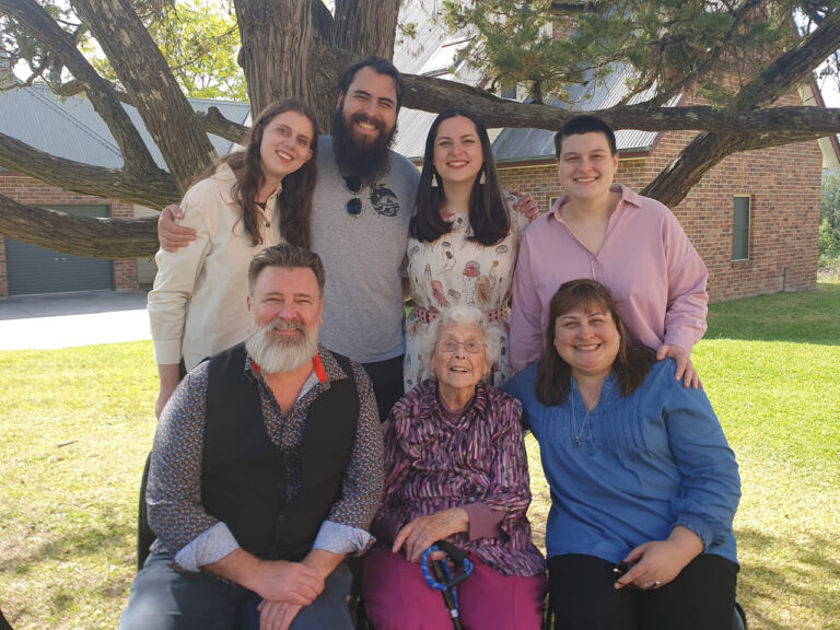 Win and her family smiling under a tree