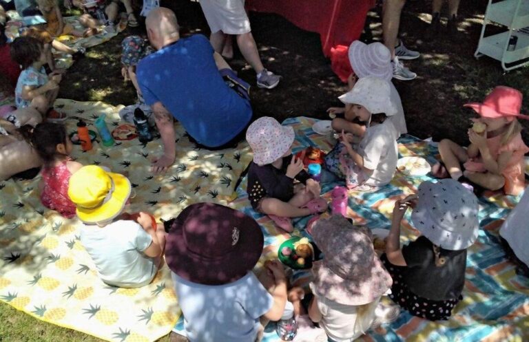 Children sitting on rugs, having a picnic