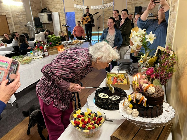 Win blowing out the candles. Sarah, Ella and Lucy (grandchildren) and friend Zoe Elliot watching on, with son Andrew onstage in background